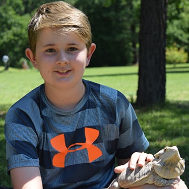 Adopt An Animal Reptiles - Camper sunbathing with bearded dragon - Cub Creek Science and Animal Camp