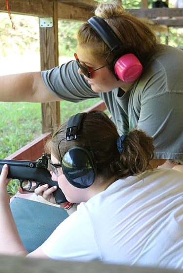 Adventure At Camp - Instructor teaching camper on riflery range - Cub Creek Science and Animal Camp